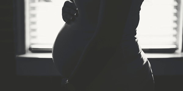 Silhouette of an expectant mother in soft window light