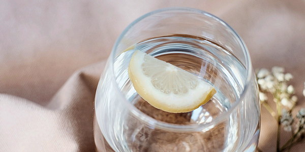A glass of lemon water resting on soft linen in the studio
