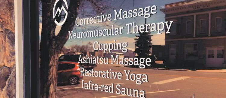 The RMCM storefront window listing corrective massage, cupping, and neuromuscular therapy